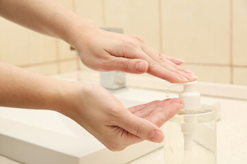 Obraz na płótnie Canvas Woman applying antiseptic gel on hand in public bathroom, closeup