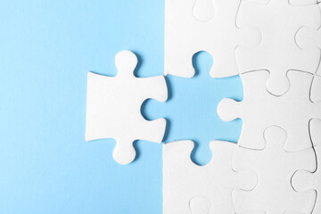 Blank white puzzle with separated piece on light blue background, flat lay