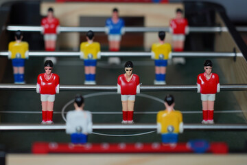 Closeup scene on table football player dolls in red and yellow shirts.