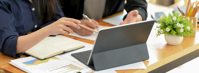 Businesswoman working with tablet, notebook and paperwork on wooden office desk