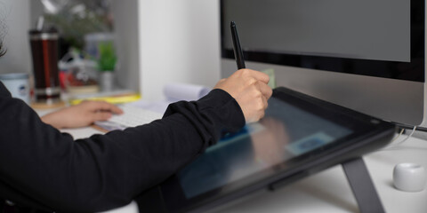 Female graphic designer working on drawing tablet and computer
