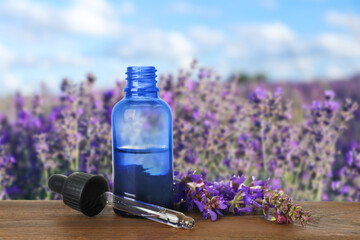 Obraz na płótnie Canvas Bottle of essential oil and sage flowers on wooden table against blurred background