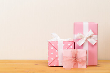 Group of gifts on a wooden table. Gift boxes with bows. beige background