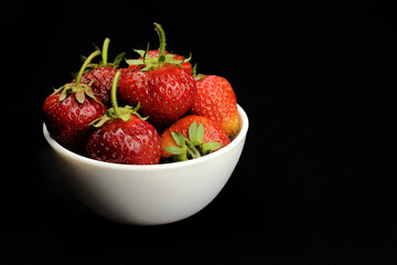 Strawberry ripe, delicious in a white bowl on a black background