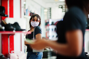 African american woman wearing face protective medical mask for protection from virus disease in shoes store during coronavirus pandemia.
