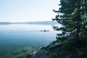 Turgoyak lake in the beginning of summer with unrecognizable person in canoe, South Ural, Russia
