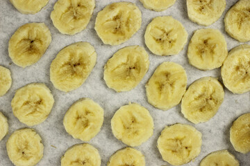 sliced banana chips on parchment paper in the oven