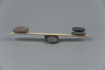 Balance, misbalance and disbalance concept. Zen stones on wooden seesaw. Concept of harmony, calm, yoga and meditation, spa, massage, relax. Zen garden.
