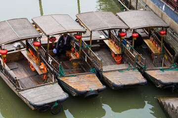 Chinese wooden boats with red lanterns parked in one of the channels in ancient Zhujiajiao town, China