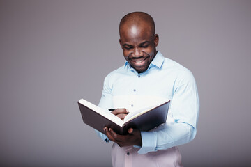 Black man in a white shirt holding a diary in his hands and checking his schedule