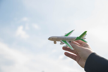 Plane in blue sky. Airplane flight permit. Man holding toy aircraft in hand. Air travel concept.