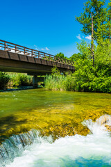 Fototapeta na wymiar Croatia, river Mreznica, beautiful waterfall and wooden bridge, green countryside landscape in Karlovac region