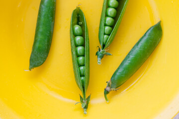 green peas pods on a yellow plate