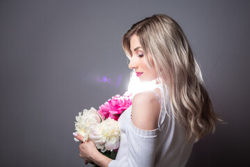 Young pretty woman with pink peonies. Spring allergy concept. space for text