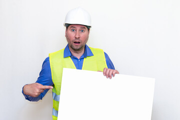 Close-up Engineer man wearing a helmet and reflector vest, standing and showing to the a paper billboard. White background.