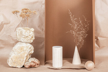 Creative podium for cosmetics or you merchandise, products. Layout made of from wooden geometric shapes, stones and dried flowers on brown beige paper background