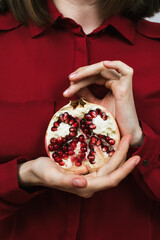 Closeup of woman's hands holding half of pomegranate