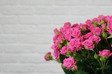 Bouquet of pink roses on a white brick wall background with copy space. The concept of flowers, floristry, holiday