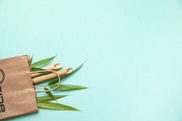 Bamboo trunks and lieaves in paper bag on green background. Eco friendly top view with copy cpace