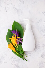 White soap or cream dispenser, leaves and flowers on white background, Organic cosmetic products mock up and herb. Skin Care. wellness, spa salon concept, self care focused, copy space