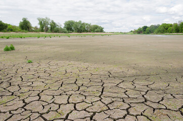 dry pond with cracked earth against a cloudy sky 6