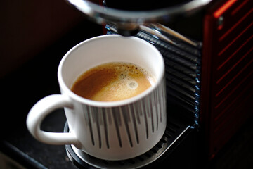 Close up a cup of coffee on coffee maker machine. Top view.