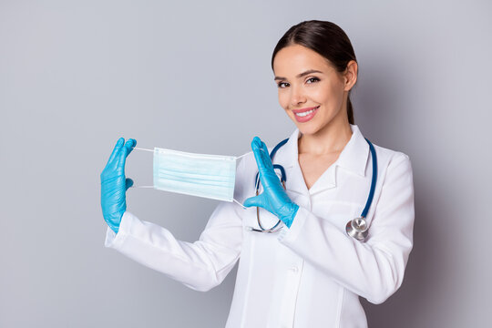 Photo of cheerful virologist doc lady professional advising patients use facial cotton mask good quality showing design wear medical uniform lab coat stethoscope isolated grey background