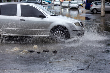 Вriving car on flooded road during flood caused by torrential rains. Cars float on water, flooding...