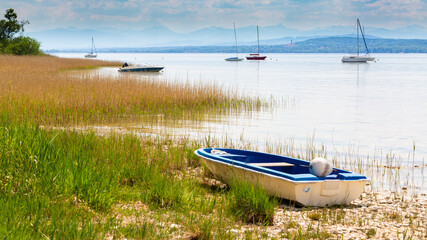 Rowing boat on the shore of Ammersee - sailboats in the background.