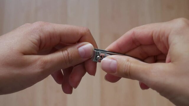 Close-up of a woman using a nail clipper to cut his nails.