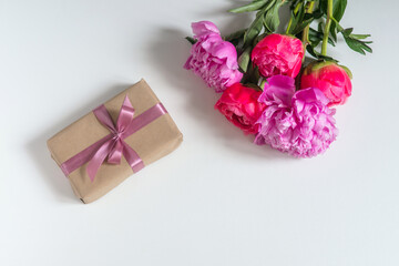 Beautiful bouquet of peonies and gift with pink ribbon