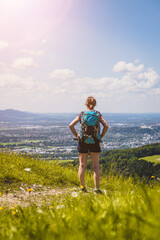 Naklejka na ściany i meble Enjoying the idyllic mountain landscape on Gaisberg: Girl is standing on idyllic meadow and enjoying the view over the far away city of Salzburg