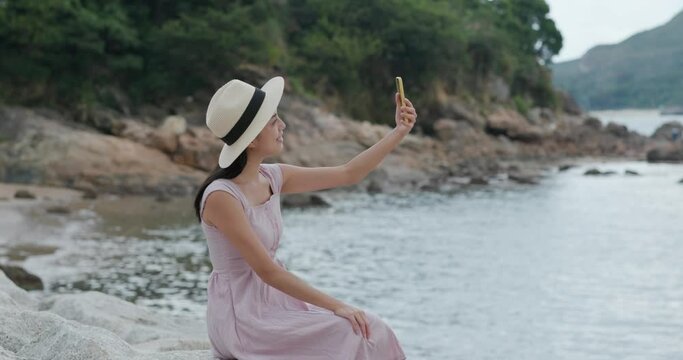 Travel woman take selfie cellphone and sit at seaside