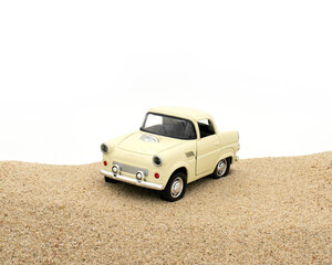 Fototapeta na wymiar Miniature cream color toy car on sand. White background