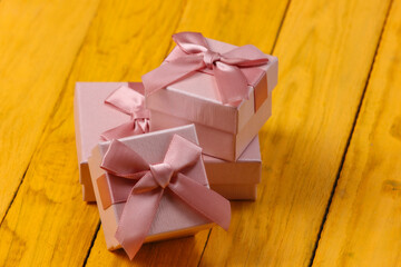 Gift boxes with bows on a yellow wooden background.
