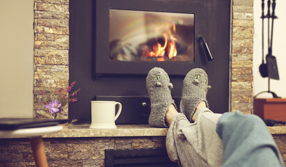 Cozy mountain weekend, Woman in cozy home wear relaxing near fireplace, drinking cocoa