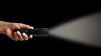 Black flashlight in human hands on a black background, including a white beam.