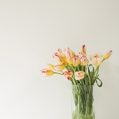 Yellow tulip flowers bouquet in glass vase against the white wall. Holiday celebration concept. Interior decoration.