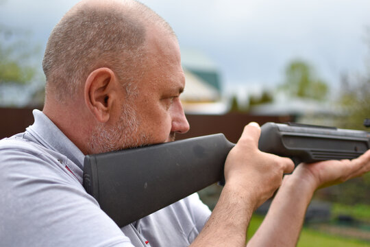 aged man with a rifle in the garden shoots at hobby targets