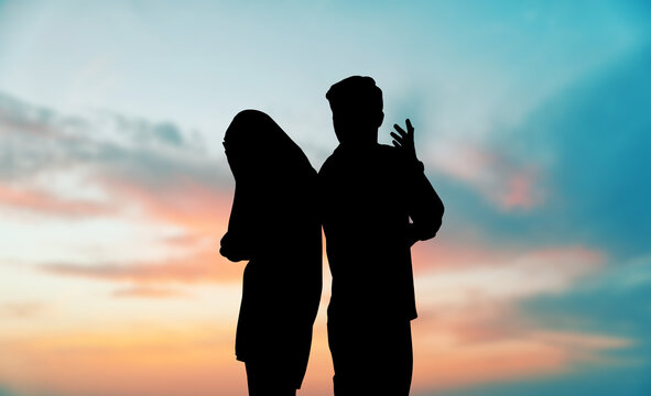 Silhouettes of arguing couple against sunset sky with clouds. Relationship problems