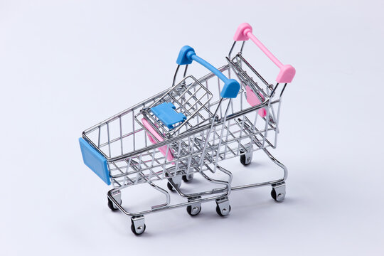 Two mini supermarket trolleys on a white background. Shopping concept.