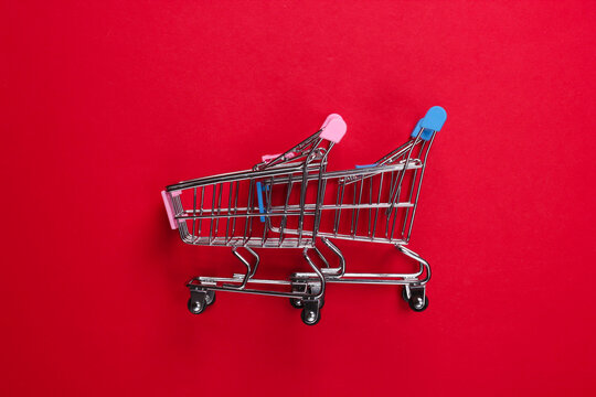 Two mini supermarket trolleys on red background. Shopping concept. Top view. Minimalism