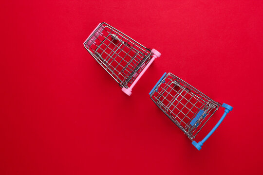 Two mini supermarket trolleys on red background. Shopping concept. Top view. Minimalism