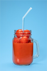 tomato juice with fresh tomatoes in a mug on a blue background