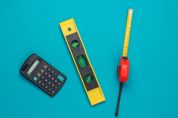 Engineering construction supplies on blue background. Construction level, ruler, calculator. Top view