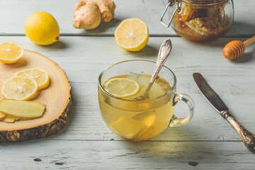 Cup of tea with lemon, honey and ginger over wooden surface