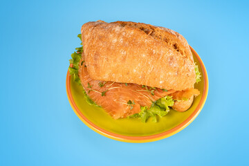 sandwich with salmon and salad on blue background