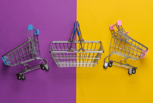 Mini Supermarket trolleys and basket on yellow purple background. Top view. Flat lay