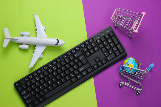 Air delivery. Global supermarket. Online shopping. Shopping trolleys with globe, keyboard, airplane figurine on purple green background. Top view. Flat lay