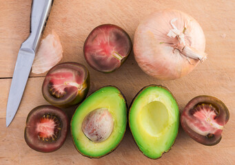 vegetables black tomatoes, avocado and onions on wooden board